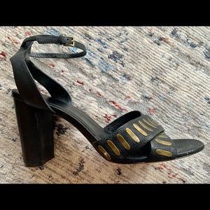 Cole Haan black leather heeled sandals with gold accents.